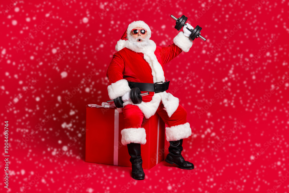 Full length photo of retired old man white beard sit giftbox hold dumbbells shocked easy workout wear x-mas santa costume glove coat belt sunglass cap boot isolated red color background Full length photo of retired old man white beard sit giftbox hold dumbbells shocked easy workout wear x-mas santa costume glove coat belt sunglass cap boot isolated red color background
