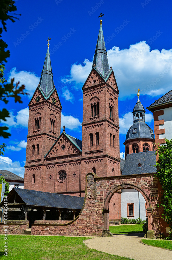 The church Basilica Seligenstadt St. Marcellinus and St. Peter of the monastery Seligenstadt as a parish church with blue sky and sunshine in summer, Seligenstadt, Hessen, Germany The church Basilica Seligenstadt St. Marcellinus and St. Peter of the monastery Seligenstadt as a parish church with blue sky and sunshine in summer, Seligenstadt, Hessen, Germany