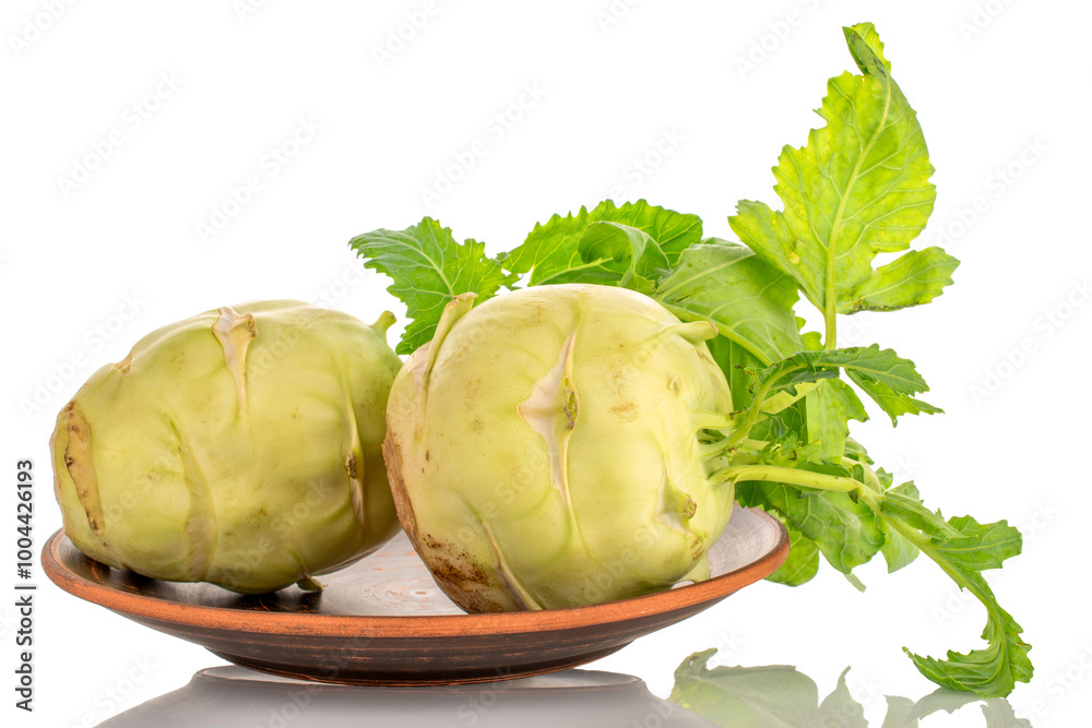Obraz premium Two ripe kohlrabi sprouts on a clay plate, macro, isolated on white background.
