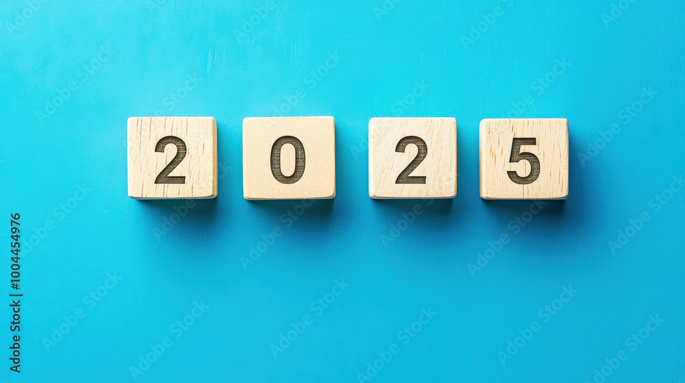 Top view of four wooden blocks displaying numbers 2025, symbolizing upcoming year and new beginnings. vibrant blue background enhances visual appeal Top view of four wooden blocks displaying numbers 2025, symbolizing upcoming year and new beginnings. vibrant blue background enhances visual appeal