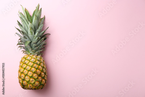 One fresh ripe pineapple on pink background, top view. Space for text