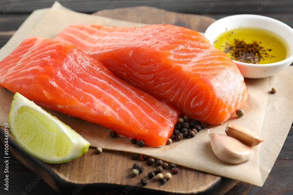 Pieces of fresh salmon, garlic, lime, oil and spices on wooden table, closeup Pieces of fresh salmon, garlic, lime, oil and spices on wooden table, closeup