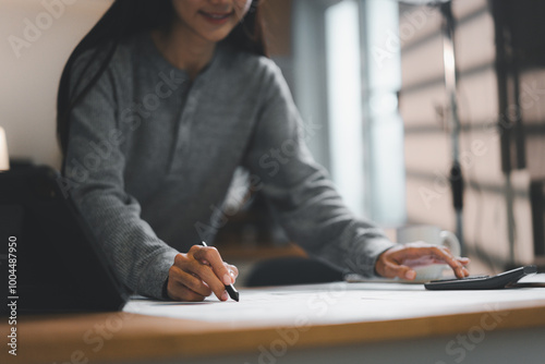 Free Download woman is focused on her work, sketching on large sheet of paper while seated at desk. atmosphere is calm and productive, showcasing creativity and concentration. - GFXLoad