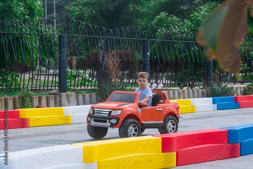 The boy is riding in a red electric car