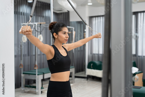 Caucasian woman training pilates using reformers during class in fitness studio 