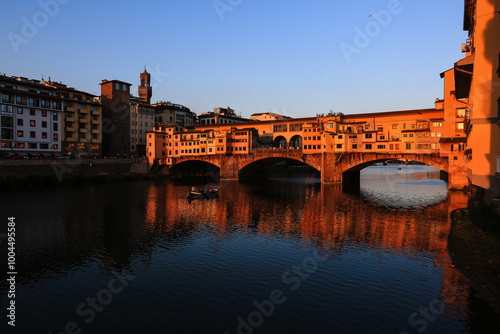 Sunset Over Ponte Vecchio in Florence, Italy
The iconic Ponte Vecchio bridge in Florence reflecting the warm sunset glow over the Arno River, with a boat passing underneath.