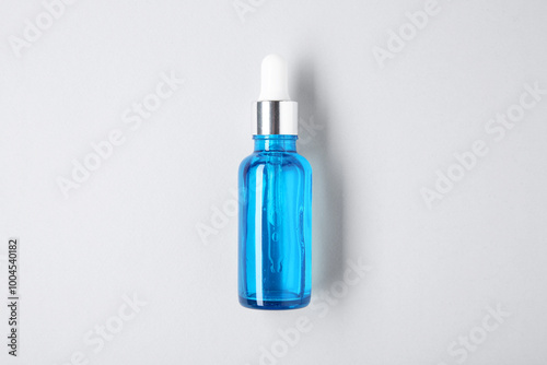 Essential oils in bottle on light background, top view