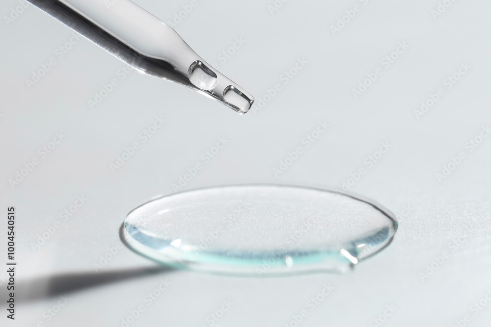Dripping cosmetic serum from pipette on light background, closeup Dripping cosmetic serum from pipette on light background, closeup