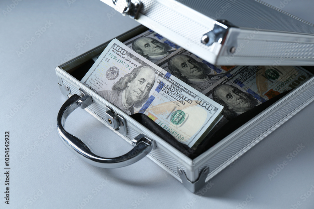 Metal case full of dollar banknotes on light background Metal case full of dollar banknotes on light background