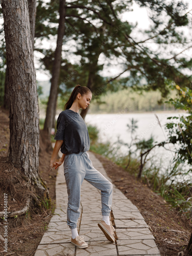 Young woman in casual outfit standing on a pathway along a river, enjoying the natural surroundings Peaceful outdoor lifestyle concept Young woman in casual outfit standing on a pathway along a river, enjoying the natural surroundings Peaceful outdoor lifestyle concept