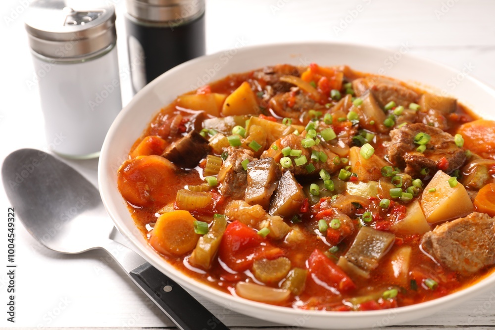 Delicious stew with vegetables in bowl and spoon on table, closeup Delicious stew with vegetables in bowl and spoon on table, closeup