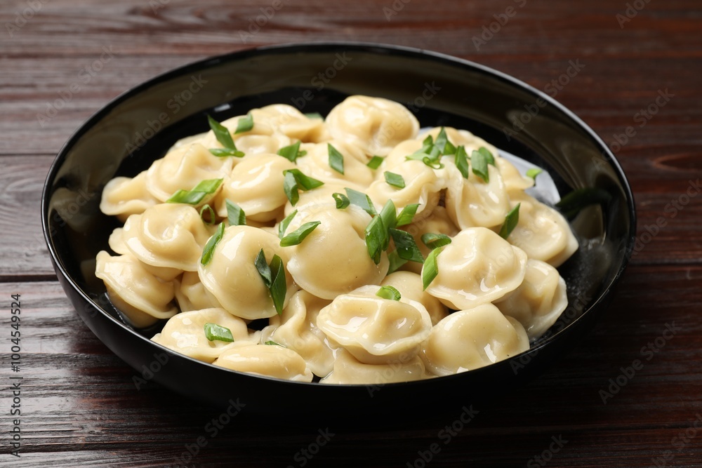 Delicious pelmeni with green onion in bowl on wooden table, closeup Delicious pelmeni with green onion in bowl on wooden table, closeup