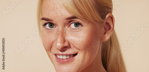 Close-up portrait of a smiling woman with blond hair and freckles. High-detailed portrait of a young cheerful female with naturally smooth skin.