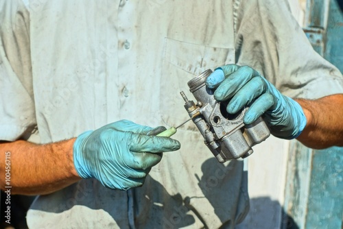 Canvas-taulu worker with hands in blue rubber gloves cleans with a sharp iron awl a green pla