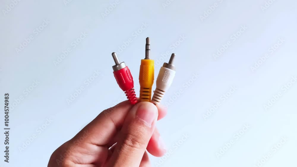 A man's hand holding an RCA cable, 3.5mm stereo jack audio cable A man's hand holding an RCA cable, 3.5mm stereo jack audio cable