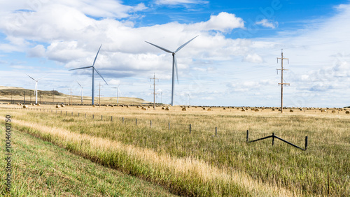 Wind power towers on  agricultural field  with bales of hay at fall season