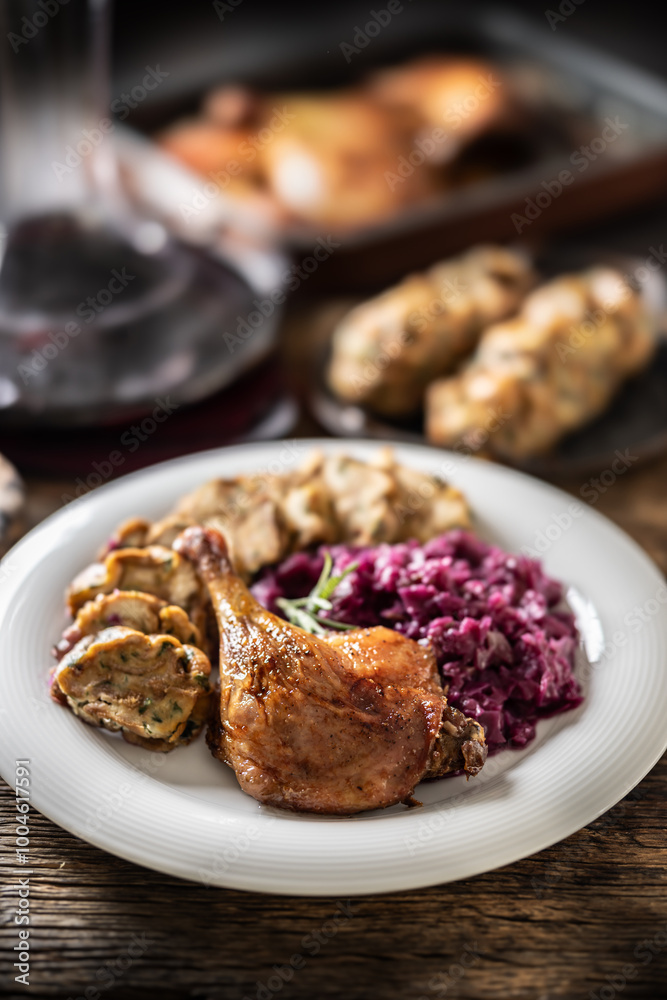 Portion of roast duck leg red cabbage homemade dumplings on plate and red wine on the background Portion of roast duck leg red cabbage homemade dumplings on plate and red wine on the background