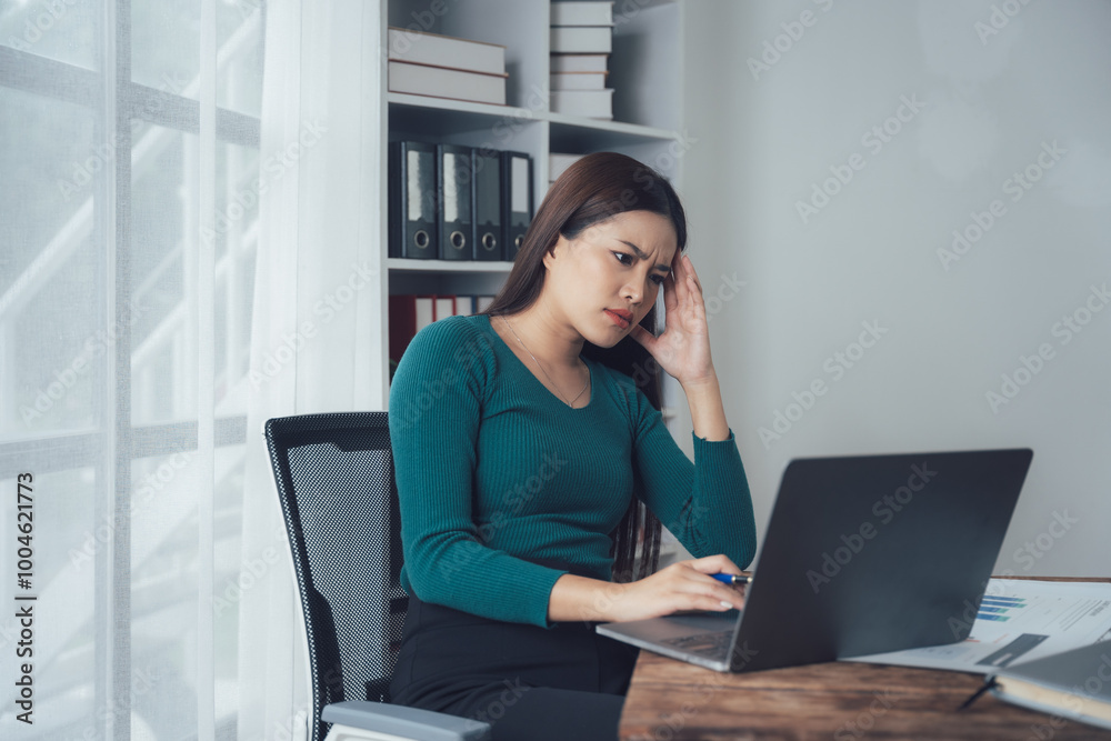 The weight of responsibility: A woman sits at her desk, her brow furrowed in concentration as she works on her laptop. The image captures the stress and pressure of modern work. The weight of responsibility: A woman sits at her desk, her brow furrowed in concentration as she works on her laptop. The image captures the stress and pressure of modern work.
