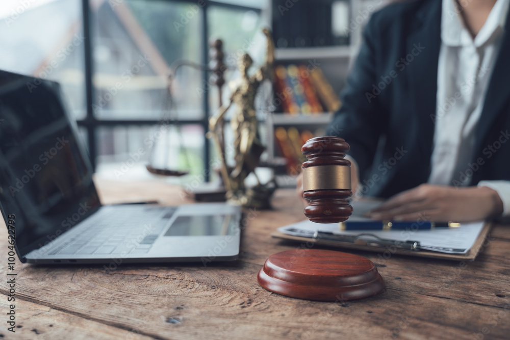 Justice Served: Lawyer's gavel on wooden desk with laptop and legal scale in the background. A symbol of legal proceedings, justice, and the law. Justice Served: Lawyer's gavel on wooden desk with laptop and legal scale in the background. A symbol of legal proceedings, justice, and the law.