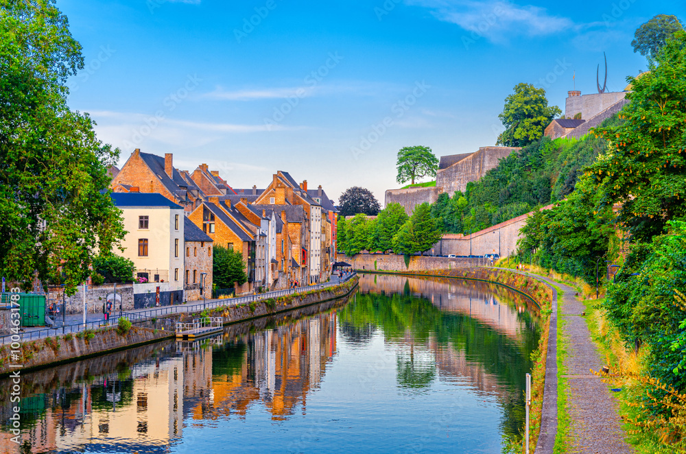 Fototapeta premium Citadel of Namur Citadelle de Namur stone fortress on hill, Sambre river embankment promenade with old colorful buildings and green trees in Namur historical city centre, Wallonia Region, Belgium