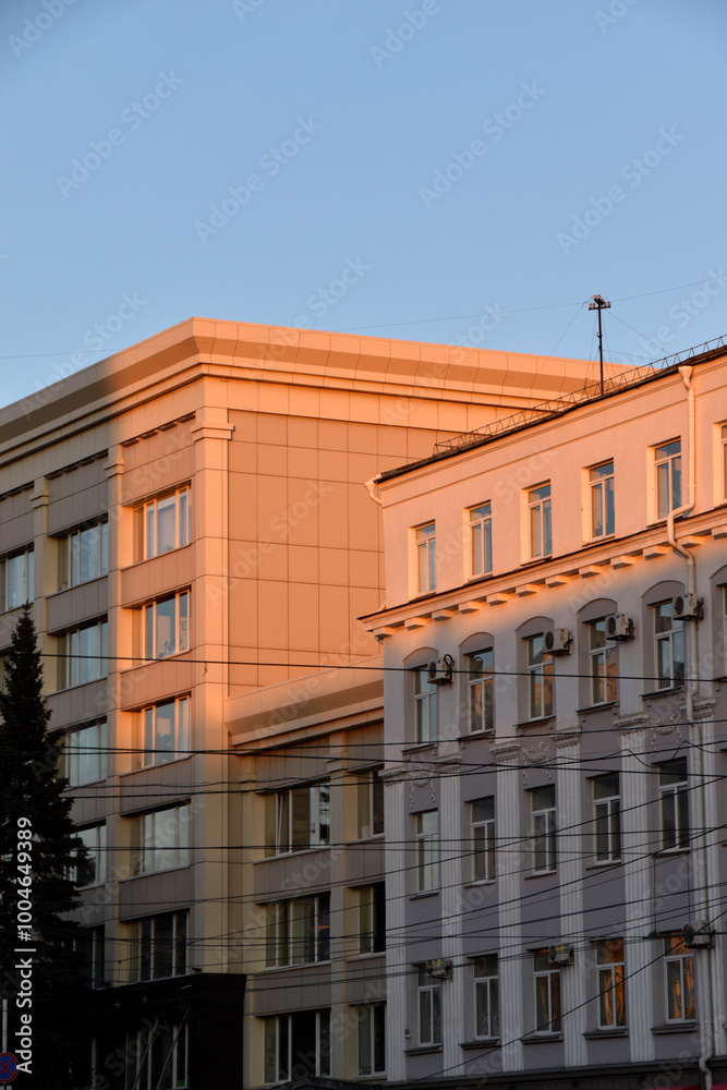 Fototapeta premium The yellow facade of the building in the evening sun. The walls of a house in the city in summer. Government buildings.