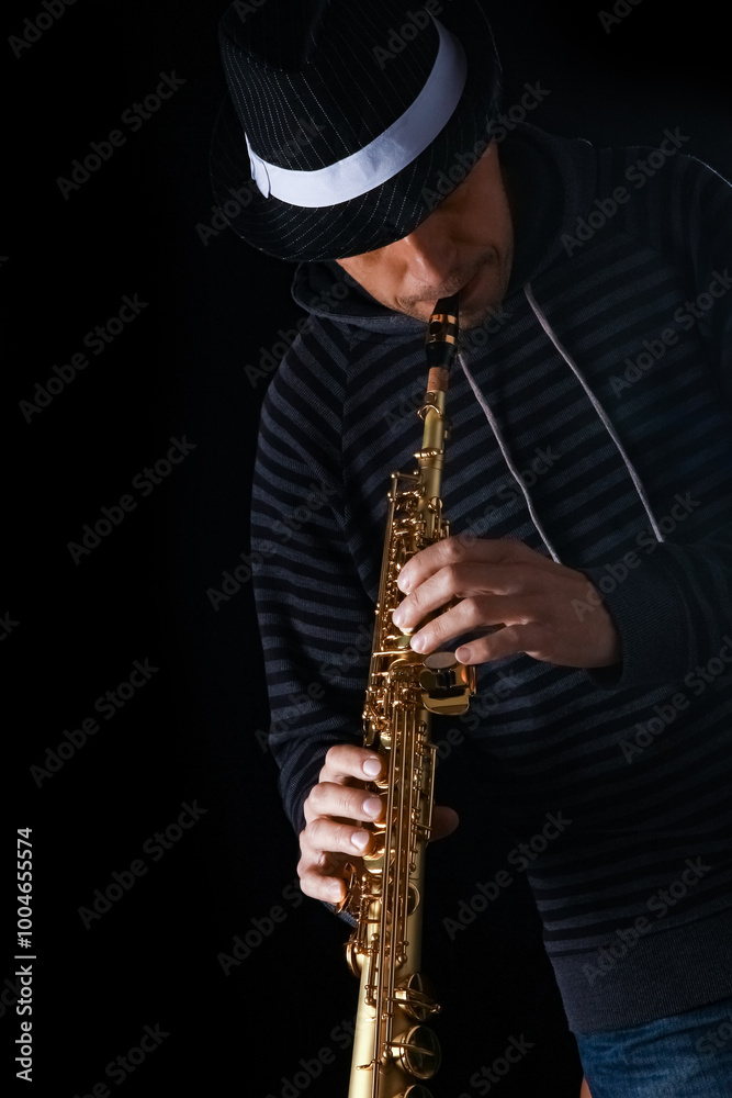 Naklejka premium soprano saxophone in the hands of a guy on a black background