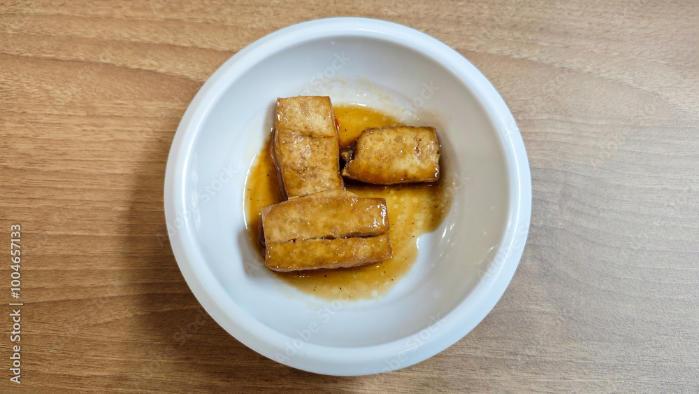 Korean Banchan with Pan-Fried Tofu Served in a White Ceramic Bowl on Wooden Table Korean Banchan with Pan-Fried Tofu Served in a White Ceramic Bowl on Wooden Table