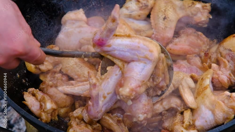 Frying chicken in a cauldron. Chicken meat in a cauldron. Outdoor cooking. Cooking in nature. Caucasian dish