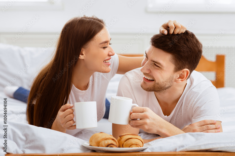 Breakfast In Bed. Happy Couple Having Coffee And Croissants Enjoying Weekend Lying In Bedroom At Home. Breakfast In Bed. Happy Couple Having Coffee And Croissants Enjoying Weekend Lying In Bedroom At Home.