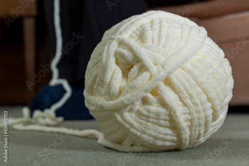 Tableau sur toile Ball of chunky chenille crochet yarn with yarn on carpet floor and leading up ou