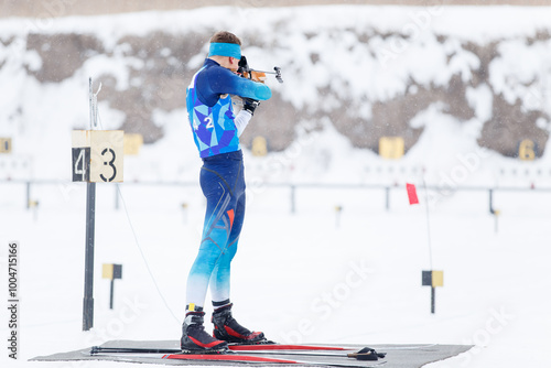 Athlete shooting in standing position at the range in a biathlon competition