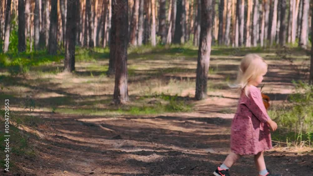 A cute toddler child girl in a dress walks in a pine forest in summer. Active childhood, lifestyle A cute toddler child girl in a dress walks in a pine forest in summer. Active childhood, lifestyle