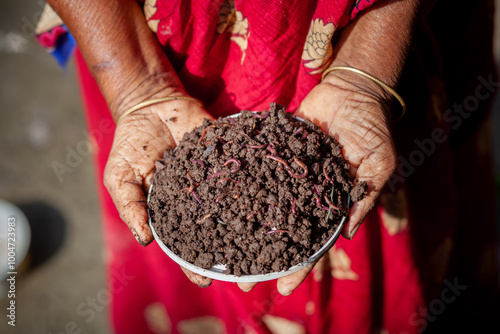 A rural woman trader displays vermicompost fertilizer in her palm.