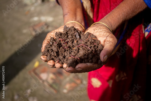 A rural woman trader displays vermicompost fertilizer in her palm.