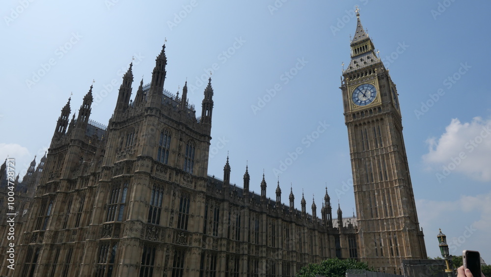 Sunny summer day in London, capturing the iconic Big Ben with clear skies. Showcasing the historic landmark's intricate architecture and its prominent place in the city's skyline.
