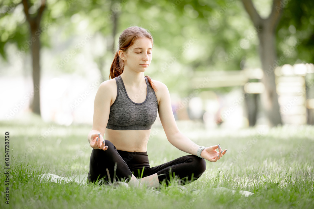 Young Girl In Lotus Pose Practices Yoga On Grass Young Girl In Lotus Pose Practices Yoga On Grass