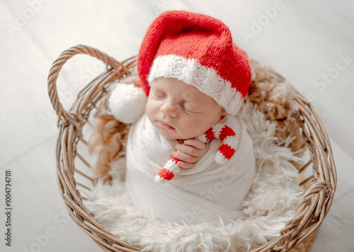 Baby Girl Sleeps In Basket In Christmas Attire With Candy Toy During Newborn Photoshoot In Studio