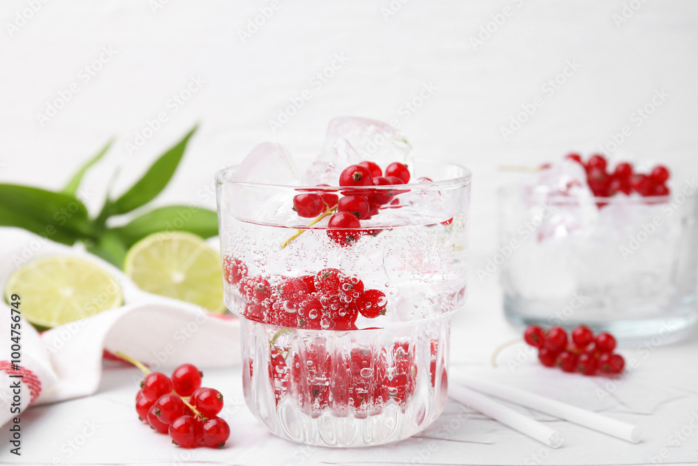 Refreshing water with red currants in glass on light table, closeup