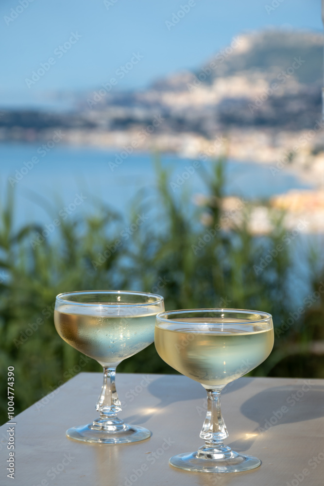 Sparkling wine, cava or champagne in two coupe glasses on table with view on blue sea, Menton and Monte-Carlo, French Riviera, France is summer Sparkling wine, cava or champagne in two coupe glasses on table with view on blue sea, Menton and Monte-Carlo, French Riviera, France is summer