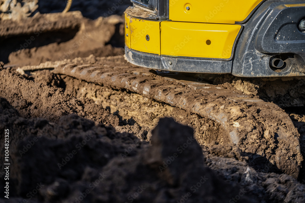 Yellow mini excavator rubber tracks very deep in the construction yard mud at least 5 inches deep Yellow mini excavator rubber tracks very deep in the construction yard mud at least 5 inches deep