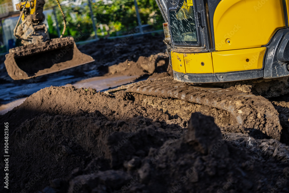 Fototapeta premium Compact and comfortable zero tail mini excavator in yellow color working in very deep mud and rough construction project terrain