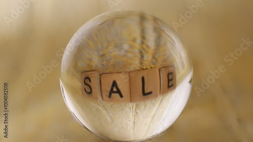 Close-up of a glass ball that reflects a yellow structure with the word Sale