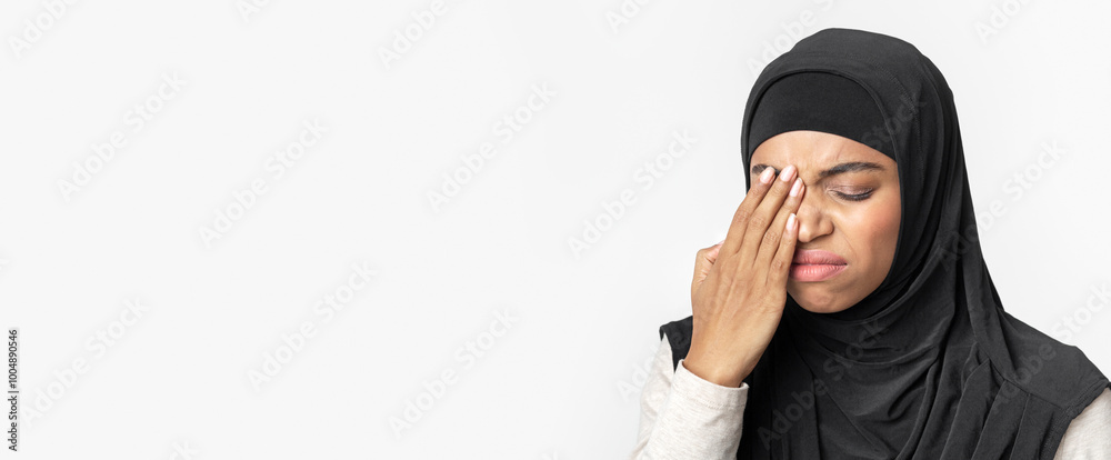 Astigmatism. Black muslim girl in hijab suffering from eye pain, touching her eyelid, feeling fatigued, light background with free space, closeup Astigmatism. Black muslim girl in hijab suffering from eye pain, touching her eyelid, feeling fatigued, light background with free space, closeup