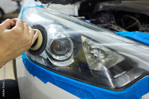 Person using a machine to polish automotive lighting on a car headlight photo