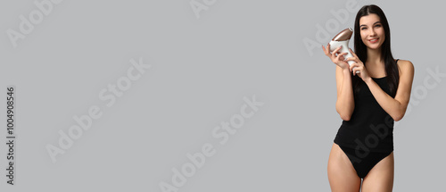 Beautiful young woman holding modern photoepilator on grey background with space for text