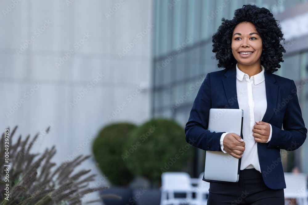 Smiling good-looking woman in a suit standing with a laptop in hands Smiling good-looking woman in a suit standing with a laptop in hands