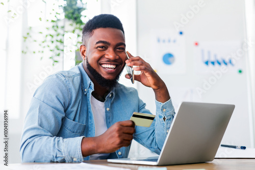 Shopping online. Cheerful african american guy talking on phone to internet shop manager, discussing details of his order while working in office.