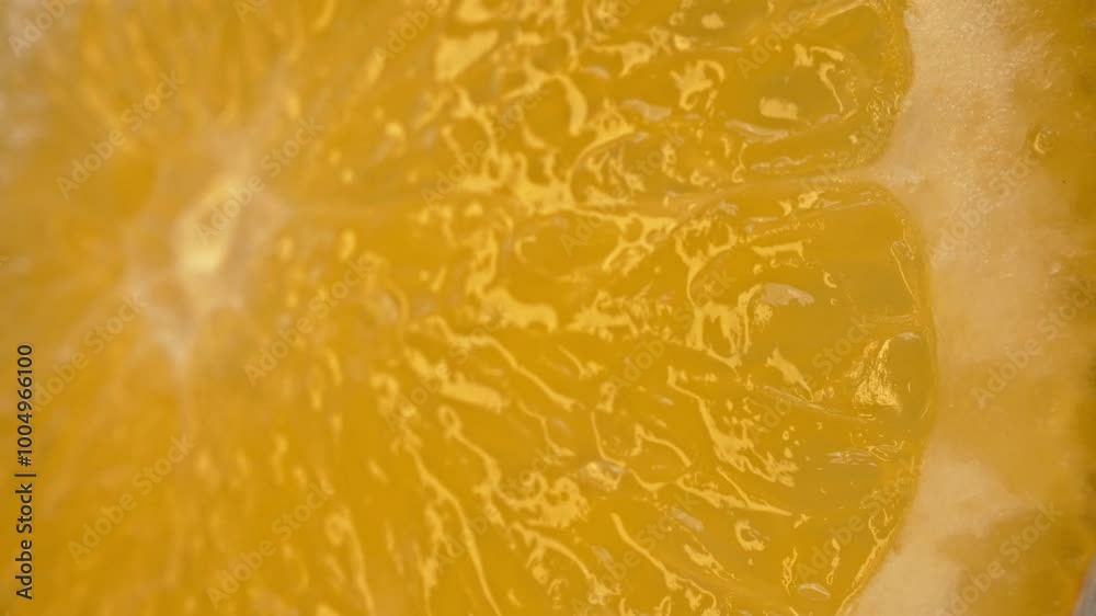 The macro photography of a sliced orange with vibrant orange color and visible in the juicy flesh of the citrus fruit. The flesh of the orange appears plump, hinting at its juiciness. Comestible.