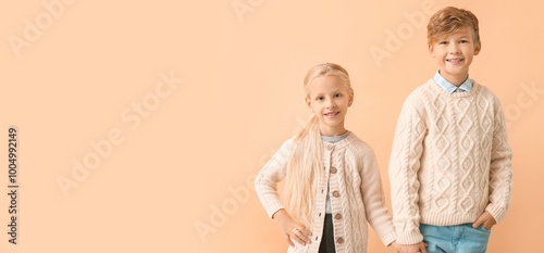 Cute little children in autumn clothes on beige background with space for text