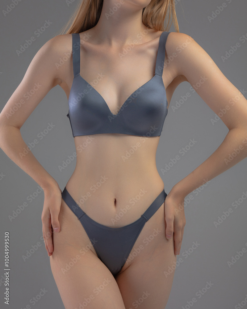 A model presents a stylish gray lingerie set in a sleek studio backdrop. She poses with hands on her hips, highlighting the design and fit of the outfit. A model presents a stylish gray lingerie set in a sleek studio backdrop. She poses with hands on her hips, highlighting the design and fit of the outfit.